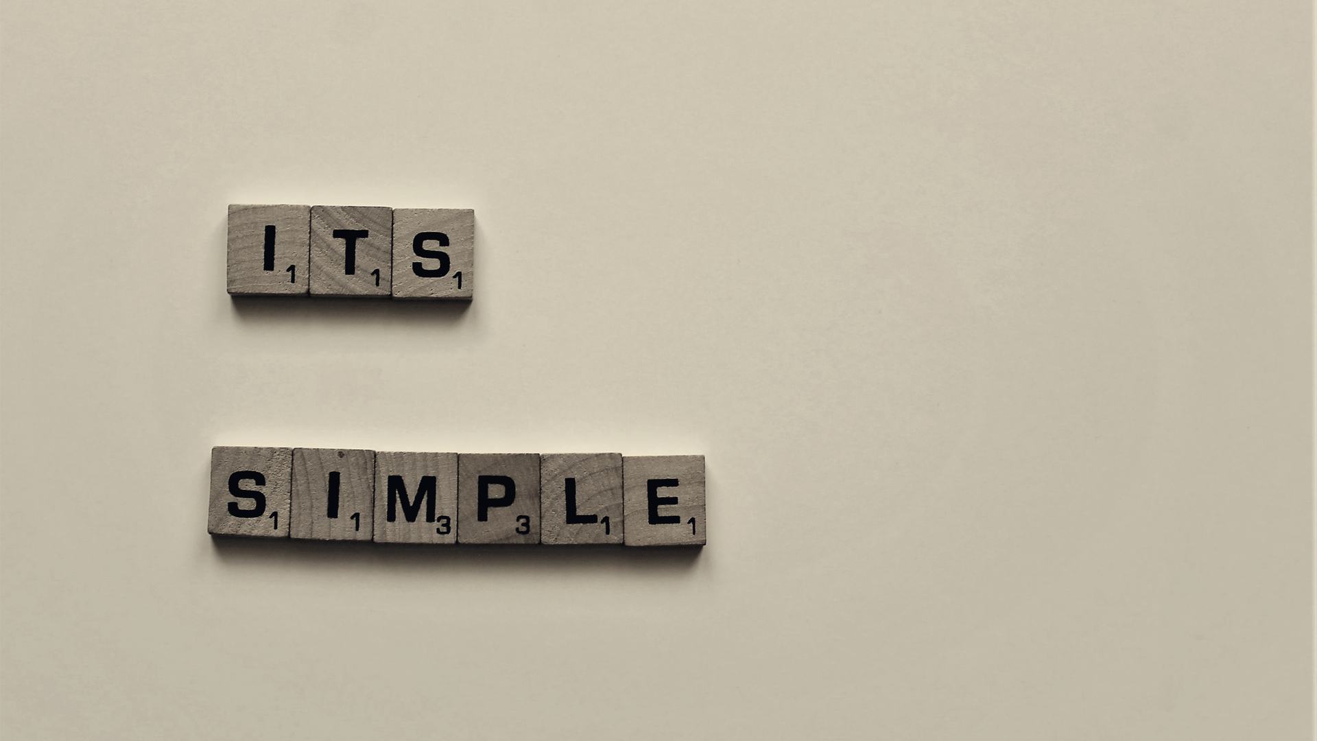 Buchstabensteine, die das Wort „simple“ legen.